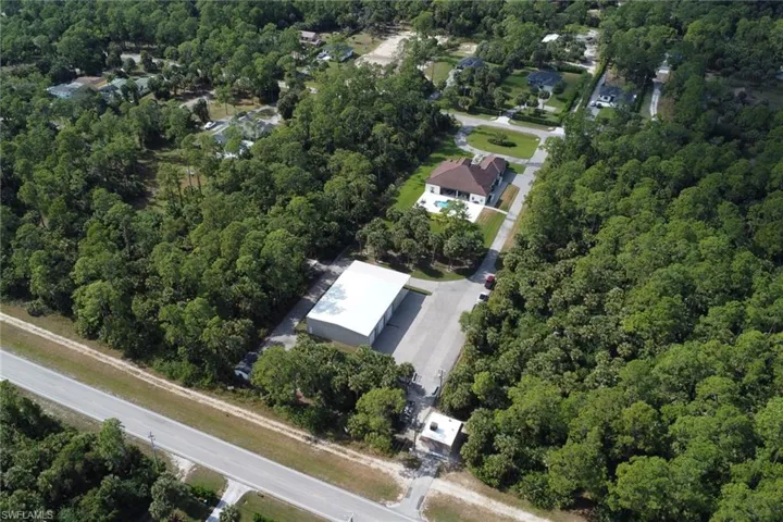 Aerial view of property and surrounding area with a heavily wooded area
