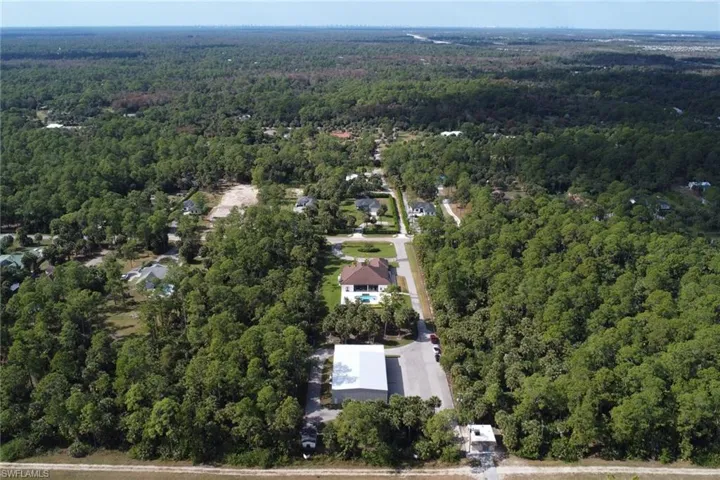 Aerial view of property and surrounding area with a forest
