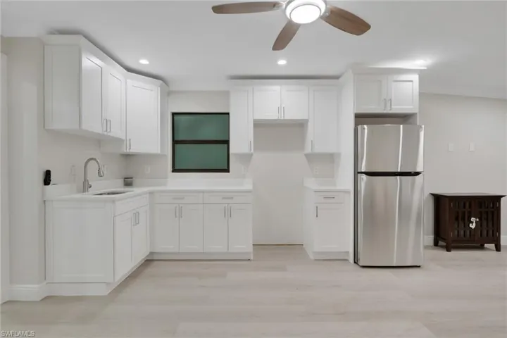 Kitchen featuring freestanding refrigerator, white cabinets, ceiling fan, and recessed lighting