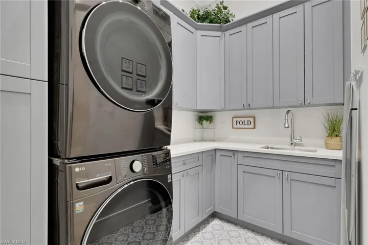 Washroom with cabinet space and stacked washer and clothes dryer