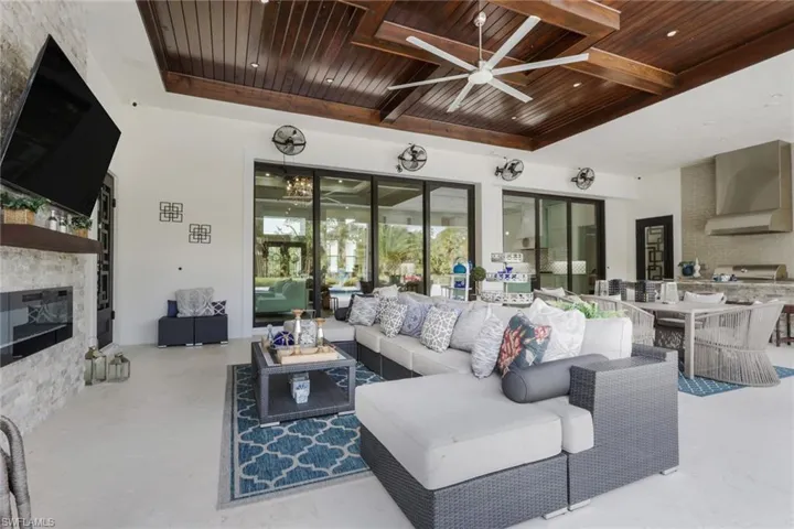 Living room with ceiling fan, a fireplace, and a wood ceiling with exposed beams