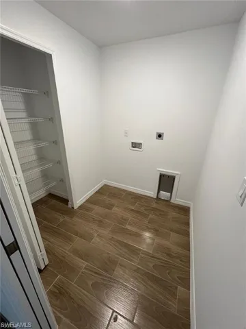 Washroom with wood finish floors and hookup for an electric dryer