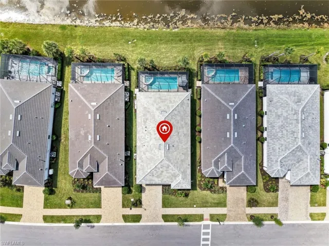 Aerial perspective highlighting a property with a light-colored tile roof, a screened-in swimming pool, and a private backyard bordering a natural waterway