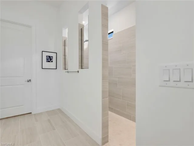 Primary Bathroom, Walk-in shower with light-toned tile, natural light window, and integrated shelving