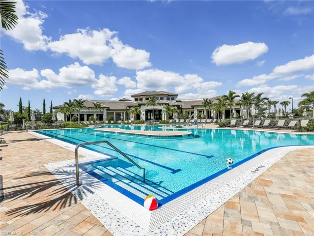 Expansive swimming pool with integrated swim lanes, surrounded by a paved deck with multiple lounge chairs