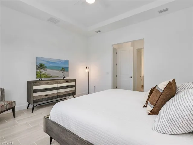 Primary Bedroom with Recessed ceiling with an overhead light fixture, light-toned tile flooring, and a white interior door