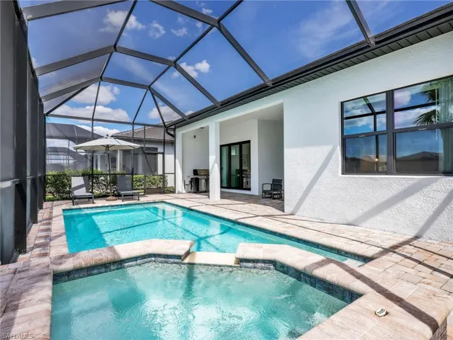 Screened-in Lanai featuring a rectangular swimming pool, integrated spa, and paver decking