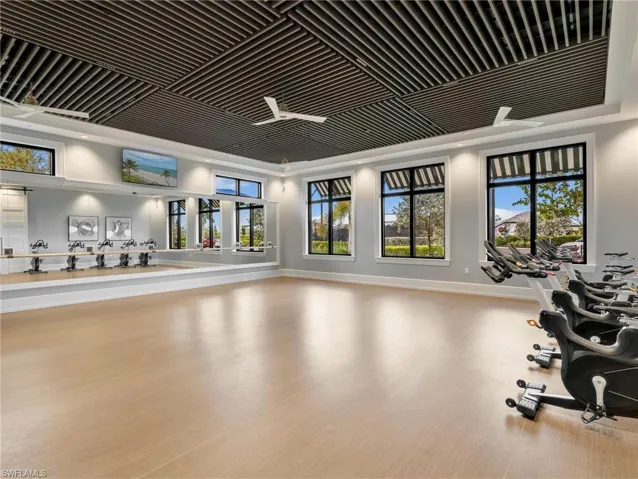 Spacious fitness area featuring wood-finish flooring, a full-wall mirror, and ample natural light through large windows