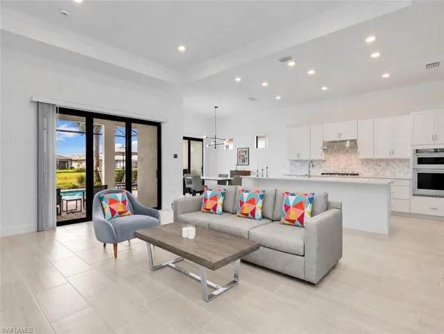 Recessed lighting, wood-finish tile flooring, sliding glass doors, white shaker cabinetry, and stainless steel appliances