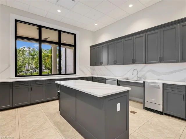 Clubhouse Spacious kitchen featuring gray shaker cabinetry, white countertops with veining, a large center island, stainless steel appliances, and a black-framed window