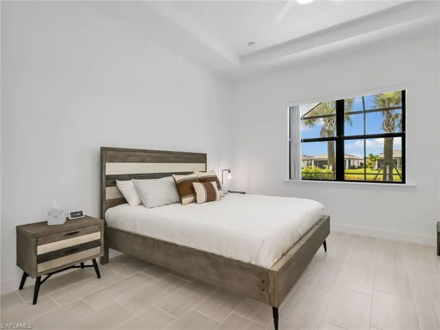 Primary Bedroom with Recessed ceiling, large window, wood-finish flooring, and white walls