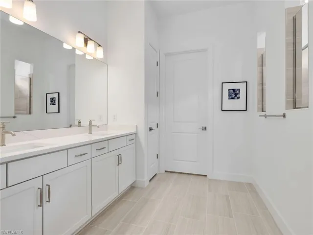 Primary Bathroom, Dual vanity with white cabinetry and brushed nickel hardware, expansive countertop space, and large wall-mounted mirror