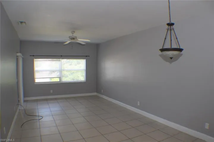 Empty room with light tile patterned floors and ceiling fan