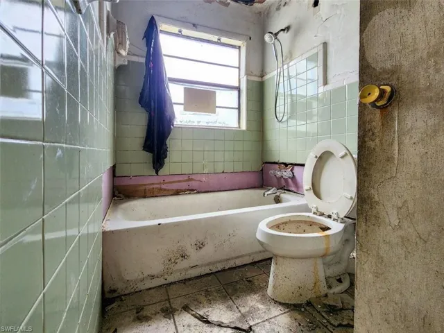 Bathroom with tile flooring, tile walls, and toilet