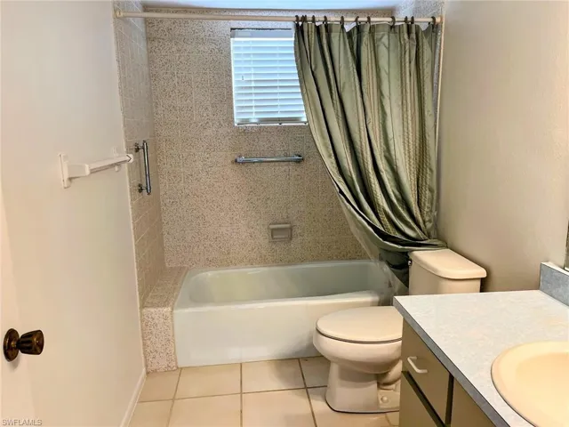 Full bathroom featuring tile patterned floors, shower / bath combo, toilet, and vanity