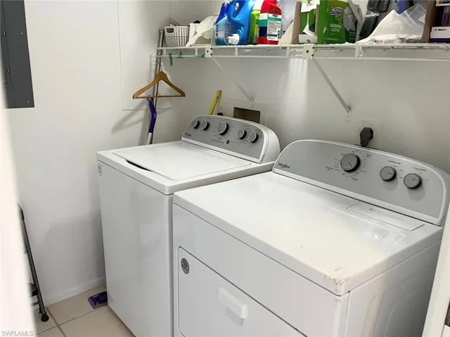 Washroom featuring washer and clothes dryer, electric panel, and light tile patterned floors