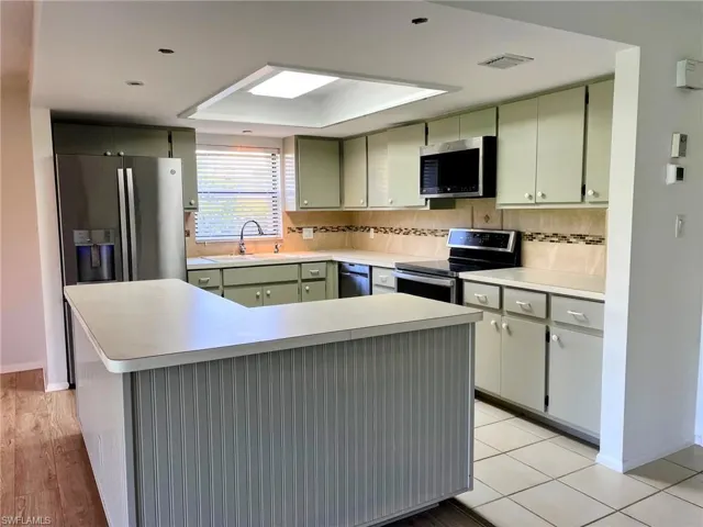 Kitchen featuring tasteful backsplash, stainless steel appliances, sink, light hardwood / wood-style flooring, and green cabinetry