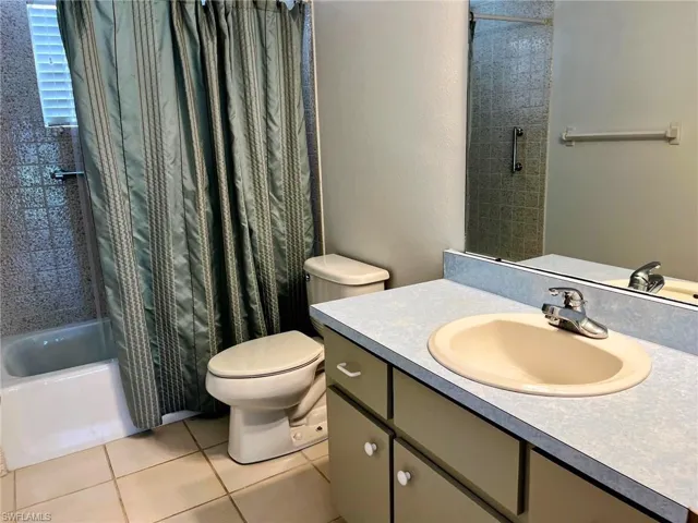 Full bathroom with vanity, tile patterned floors, toilet, and shower / bath combination with curtain