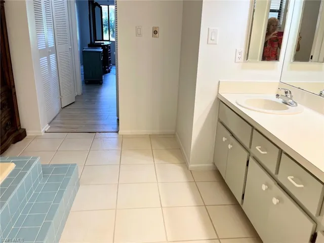Bathroom with vanity, tiled tub, and hardwood / wood-style floors