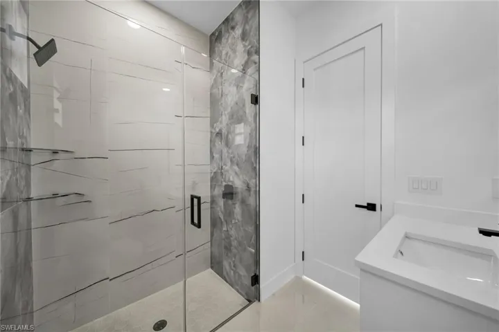 Bathroom featuring a marble finish shower and vanity