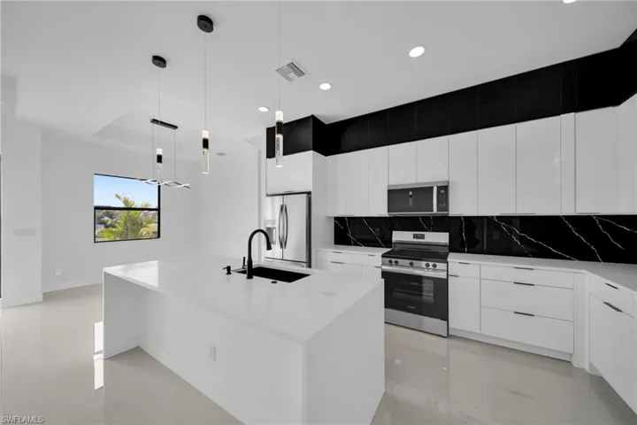Kitchen with modern cabinets, decorative backsplash, stainless steel appliances, hanging light fixtures, and recessed lighting