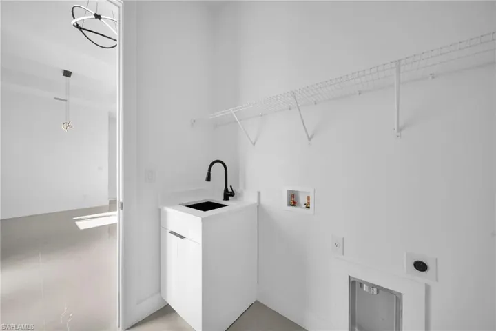 Laundry room with light tile patterned floors, washer hookup, electric dryer hookup, and a chandelier