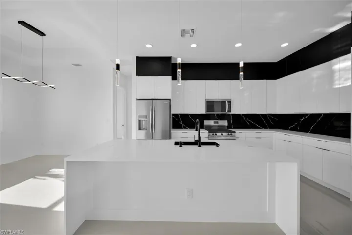 Kitchen featuring modern cabinets, white cabinetry, pendant lighting, backsplash, and recessed lighting
