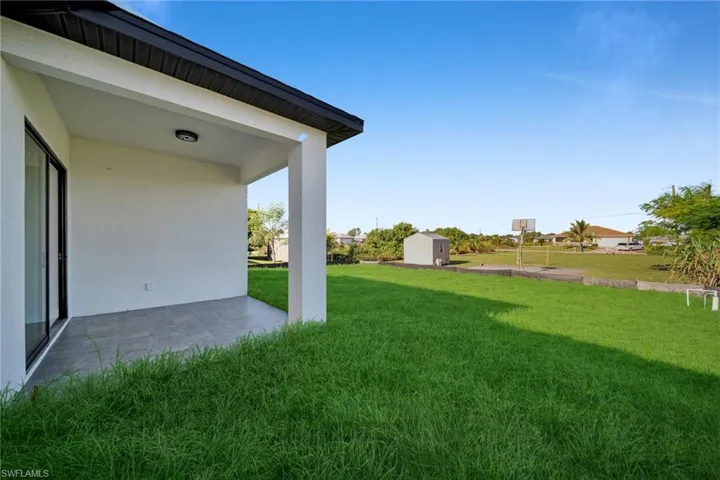 View of green lawn featuring a patio area and a storage unit