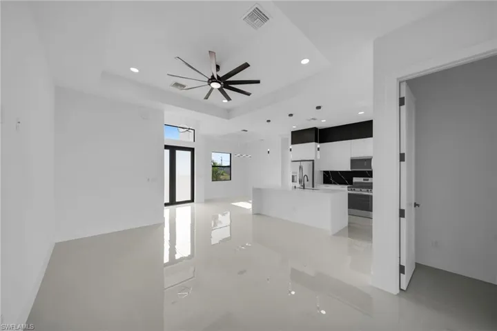 Unfurnished living room with a tray ceiling, recessed lighting, ceiling fan, and light tile patterned floors