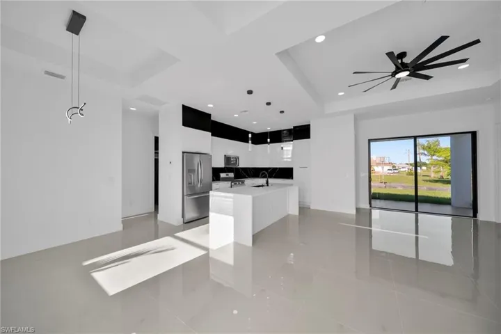 Kitchen with a raised ceiling, open floor plan, light tile patterned floors, an island with sink, and modern cabinets