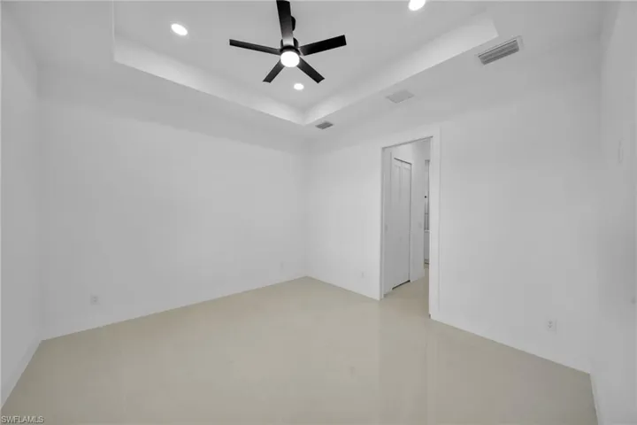 Spare room with a raised ceiling, recessed lighting, and ceiling fan