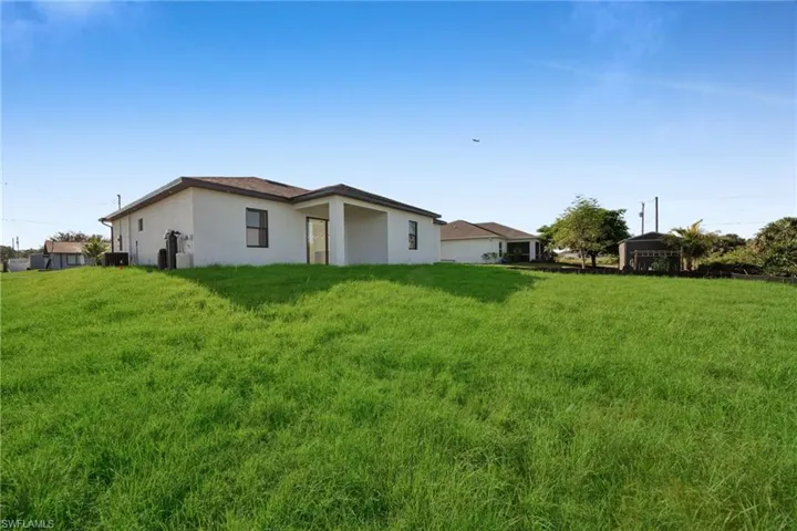 Back of house featuring stucco siding and a yard