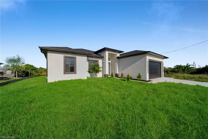 Prairie-style house featuring concrete driveway, stucco siding, a front yard, and a garage