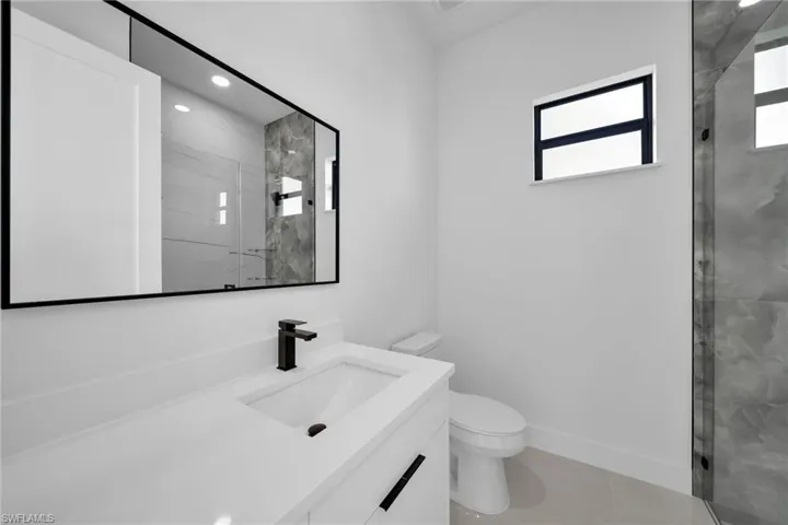Bathroom featuring vanity, a marble finish shower, and light tile patterned flooring