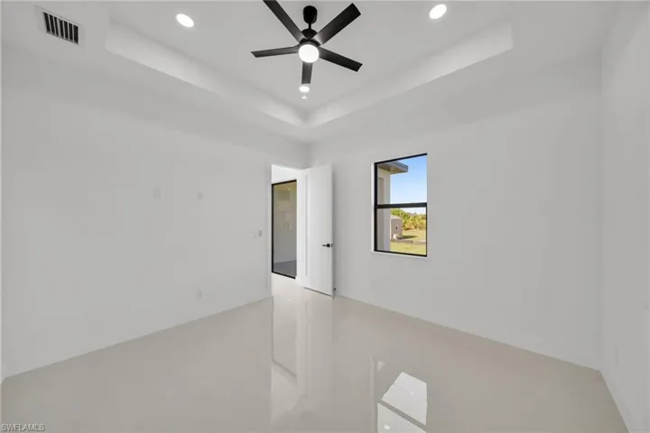 Empty room with a tray ceiling, recessed lighting, and ceiling fan