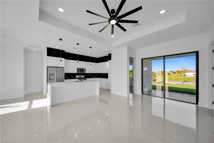 Unfurnished living room featuring a raised ceiling, recessed lighting, light tile patterned flooring, and a ceiling fan