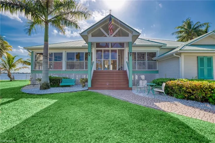 View of front of home featuring a front yard, a patio area, a sunroom, a wooden deck, and stairway