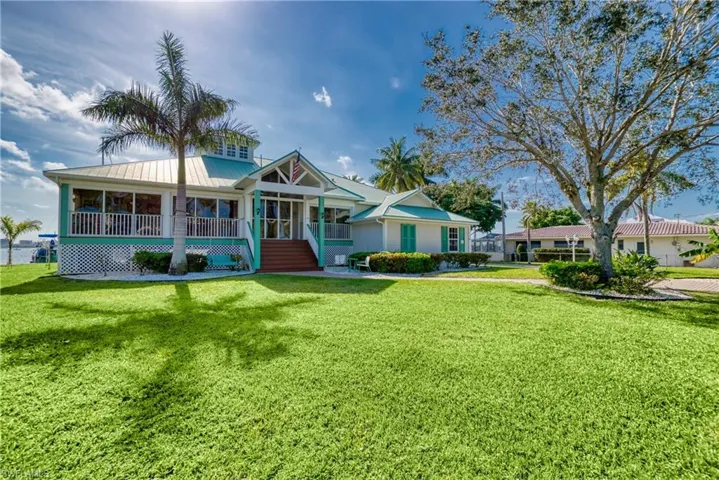 View of front of property with a porch, a front lawn, a metal roof, and stairs
