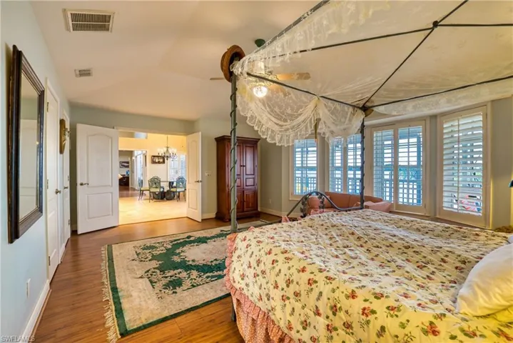 Bedroom featuring wood finished floors, vaulted ceiling, and a chandelier
