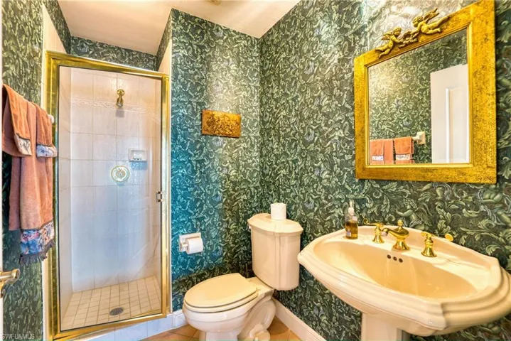 Bathroom featuring wallpapered walls, a shower stall, and tile patterned floors