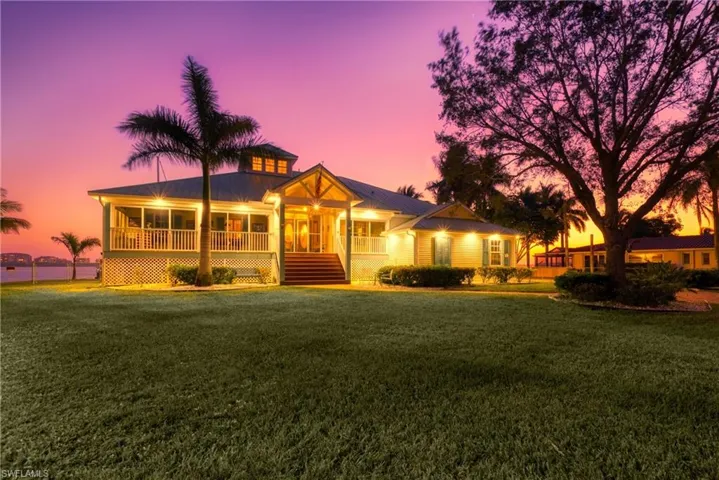 View of front of property with a porch, a metal roof, a front lawn, and stairs