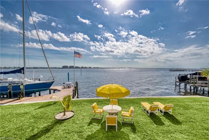 Dock area with boat lift, a lawn, and a water view