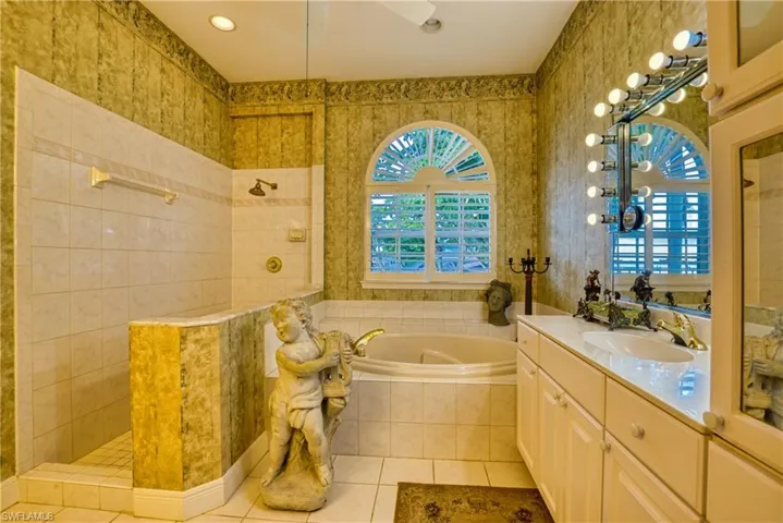 Bathroom with a walk in shower, vanity, wallpapered walls, light tile patterned flooring, and a bath