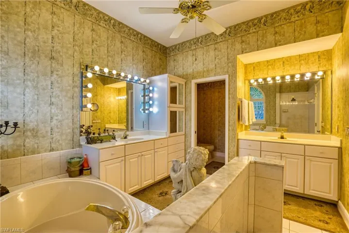Bathroom with two vanities, a bath, light tile patterned floors, a tile shower, and ceiling fan