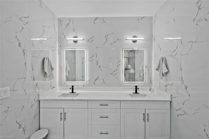Dual vanity with white cabinetry, matte black faucets, and rectangular undermount sinks