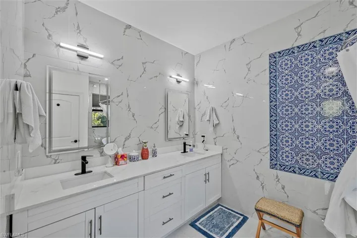 Bathroom featuring a dual vanity with white cabinetry, integrated sinks, and black fixtures