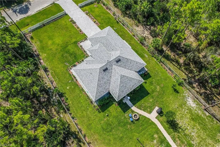 Expansive property featuring a multi-gabled roofline, a lengthy paved driveway, and lush green lawns
