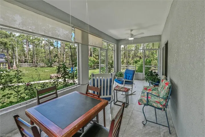 Screened porch featuring a tiled floor, white ceiling fan, and textured wall finish
