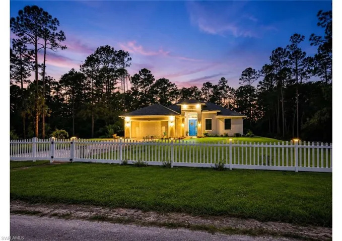 Single-story residence featuring a blue entry door, an attached garage, and exterior lighting