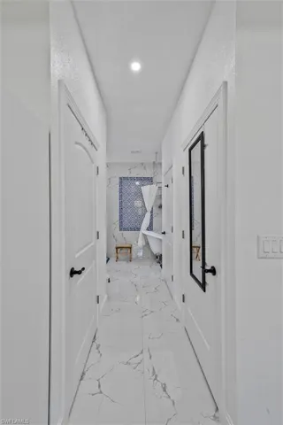Hallway featuring white panel doors with matte black hardware, white walls, and recessed lighting